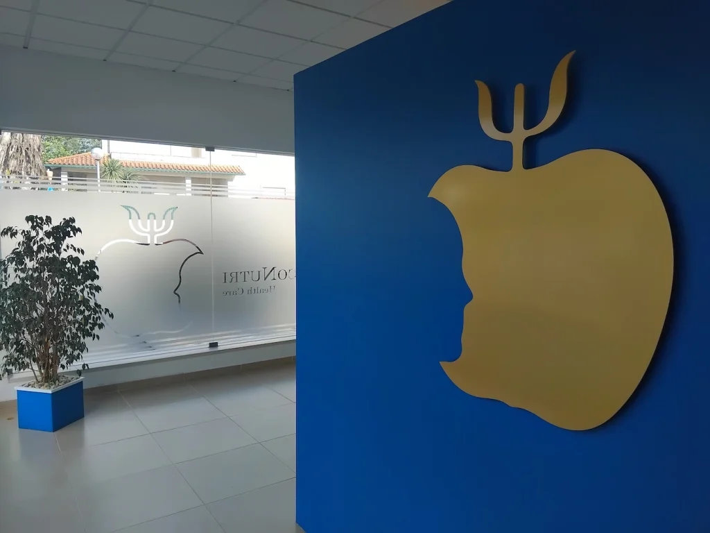 Entrada da clínica PsicoNutri Health Care com logótipo dourado e divisória envidraçada